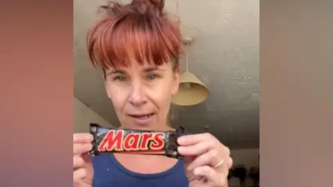 Женщина держит старый батончик Mars
