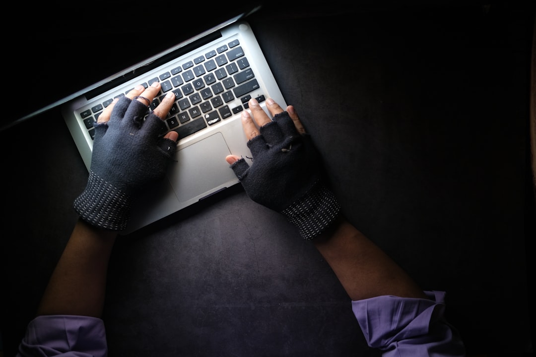Человек в чёрной кофте с длинным рукавом работает за MacBook Pro