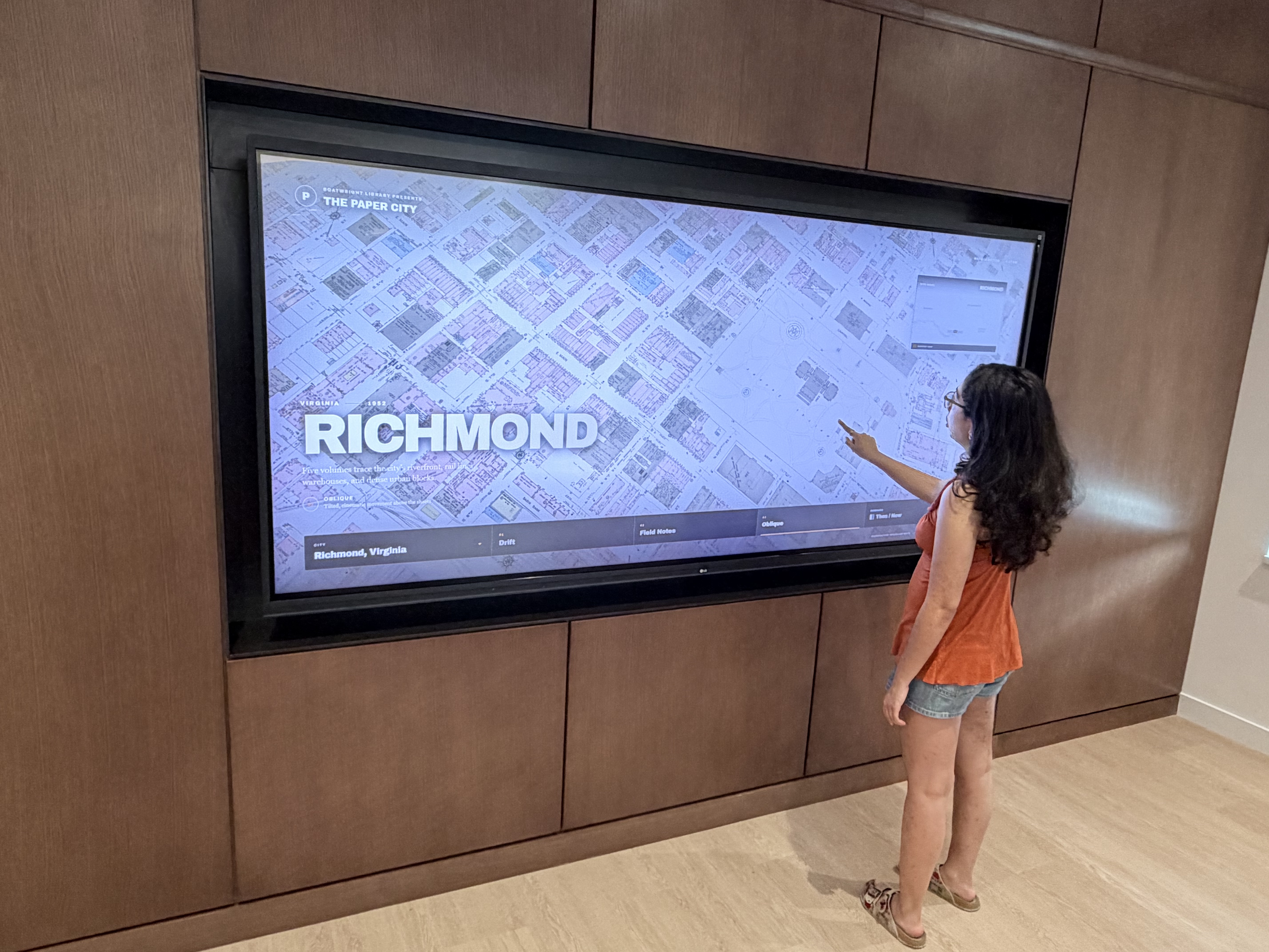A student standing in front of a large digital display of a Sanborn map