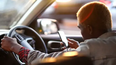 Водитель Uber смотрит в телефон в ожидании клиента