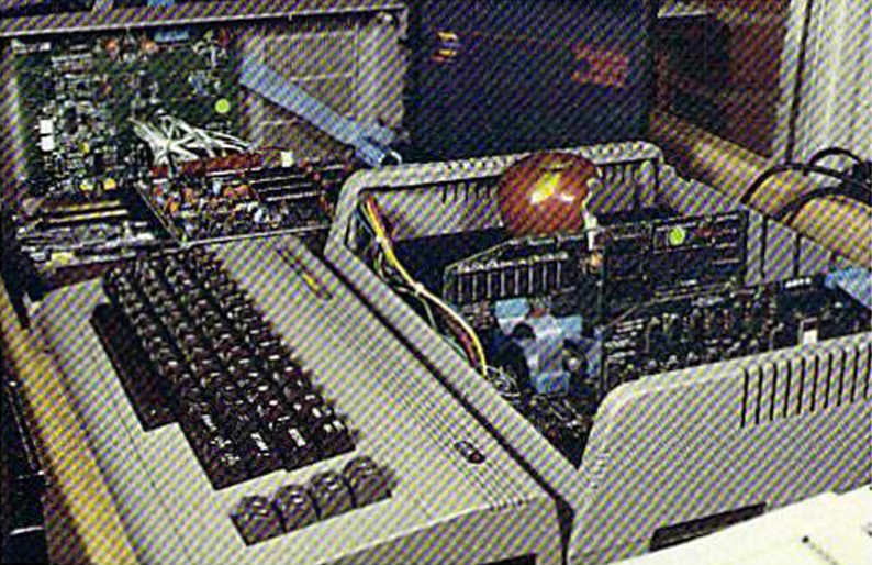Commodore 64, подключённый к машине Spartan, стоит на столе. На Spartan снята крышка, и яблоко сидит на открытом блоке питания.