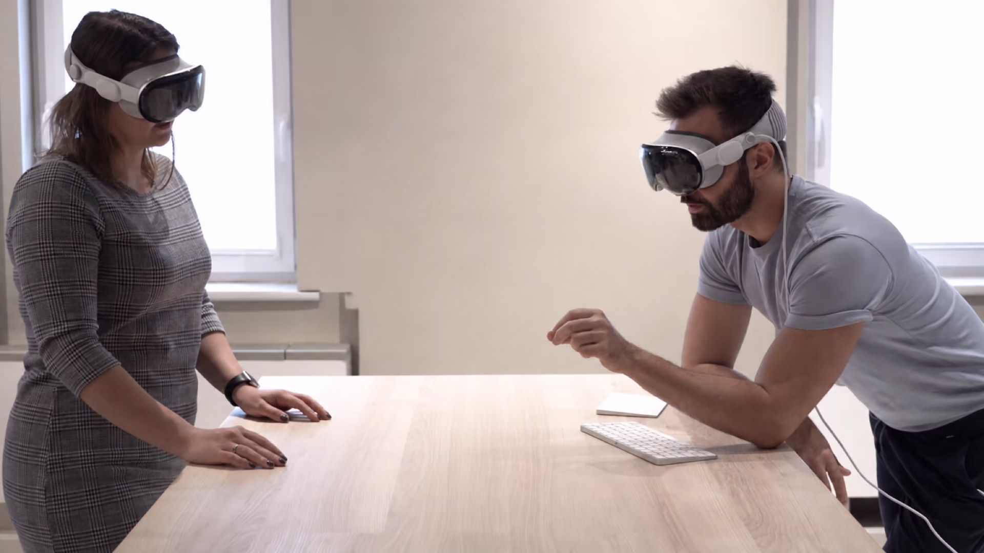 Два человека через стол, каждый в Vision Pro, без визуализированного виртуального контента